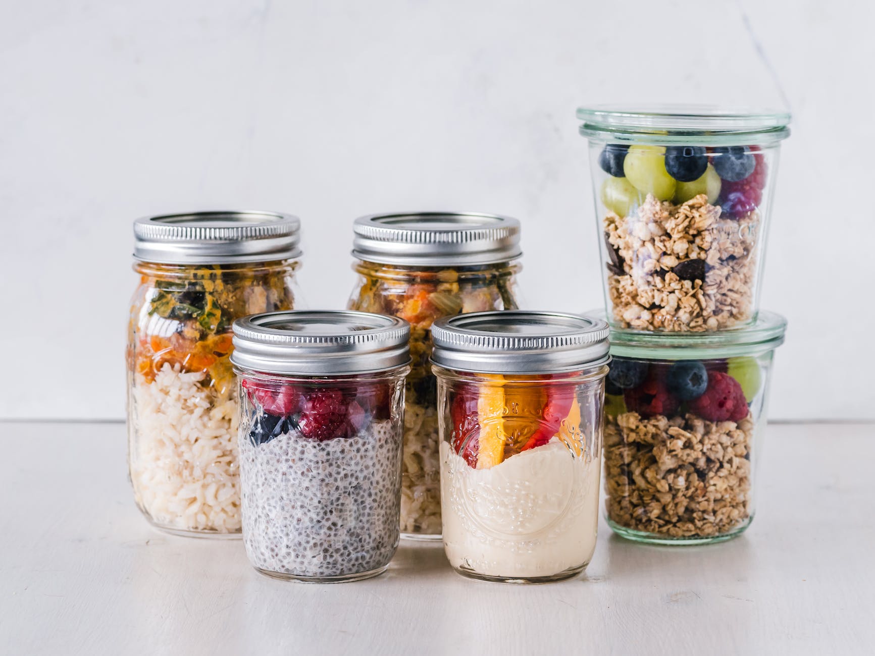 six fruit cereals in clear glass mason jars on white surface - fibre for healthy gut flora