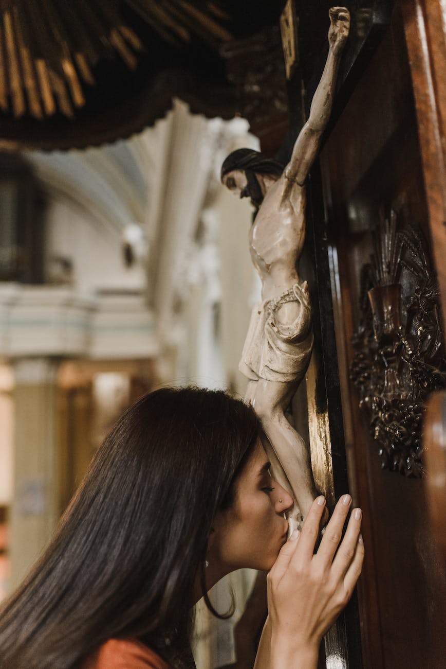 a woman kissing the sculpture of jesus christ