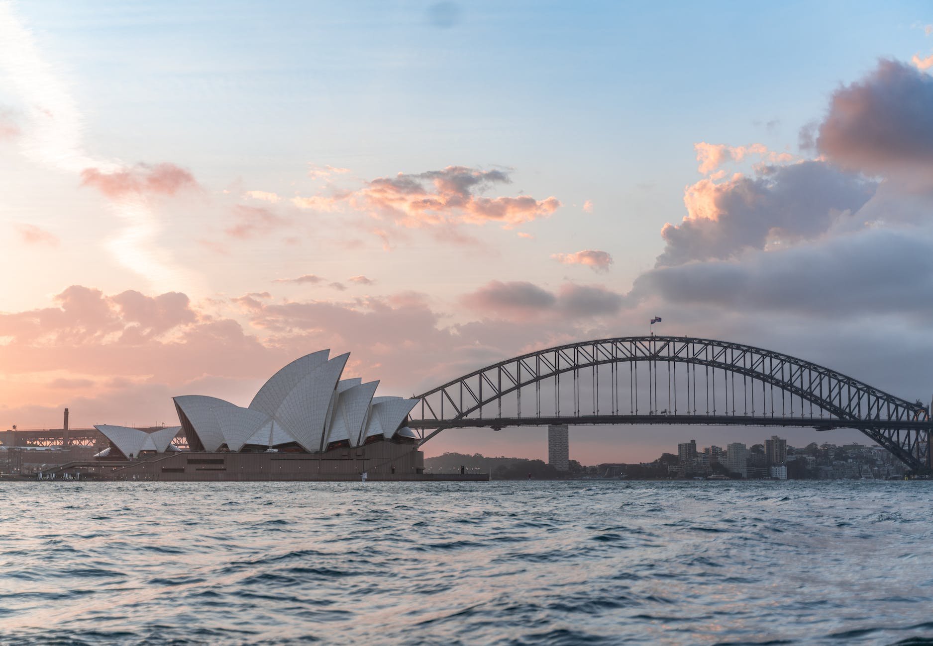 stylish modern building and arch bridge crossing harbor against cloudy sundown sky Australia Has Set The Bar Too Low