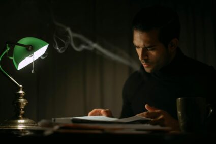 serious man reading book in dark room