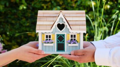 people holding miniature wooden house